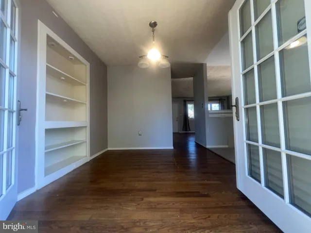 a view of an empty room with closet and wooden floor
