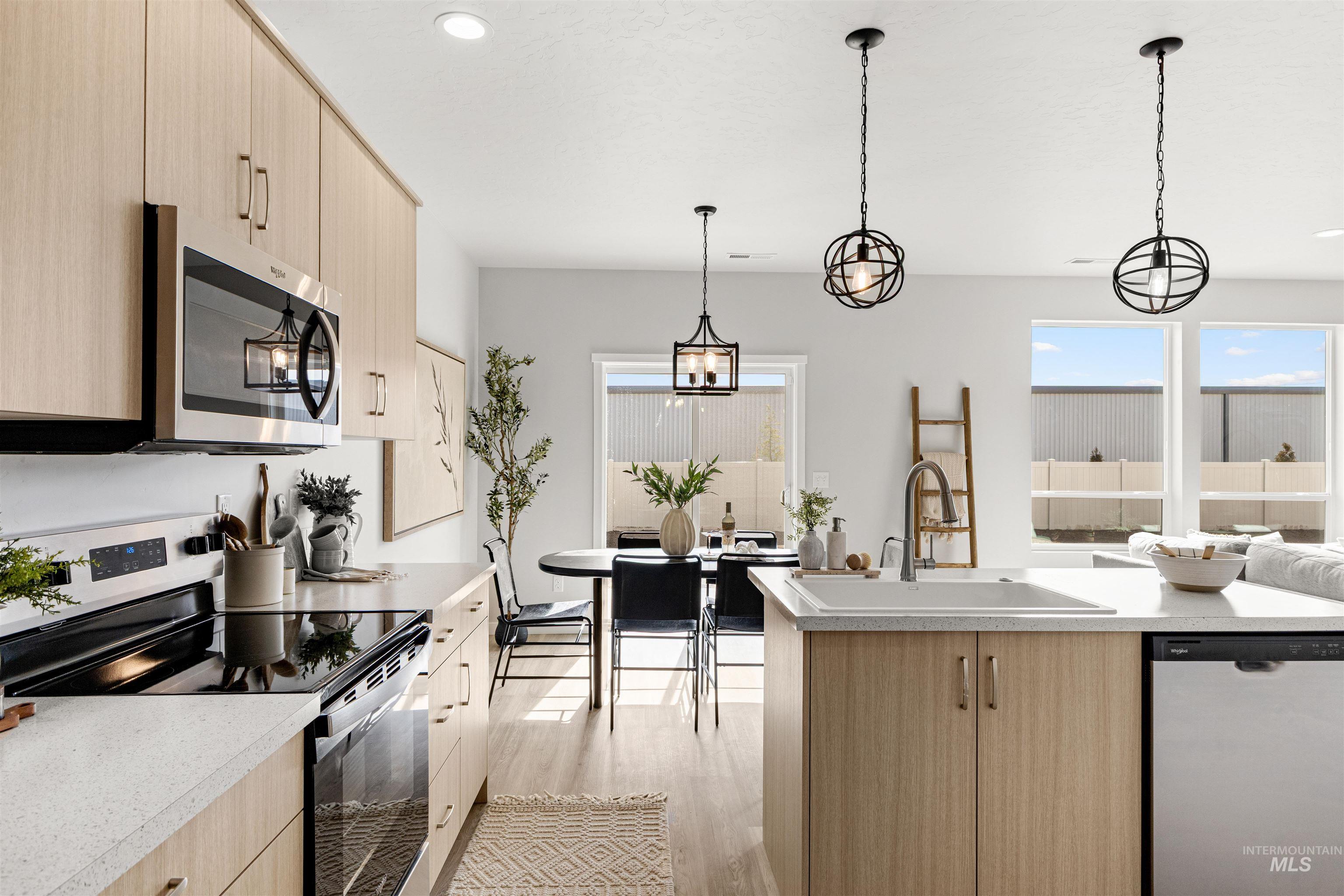 2526 West Fallon Loop Nampa, ID 83651 - Photo 12 of 32 Kitchen with light wood finish cabinetry, stainless steel appliances, light countertops, decorative light fixtures, and light wood-type flooring