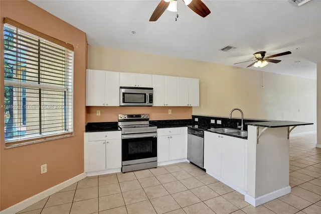 a view of a hallway with wooden floor and a kitchen