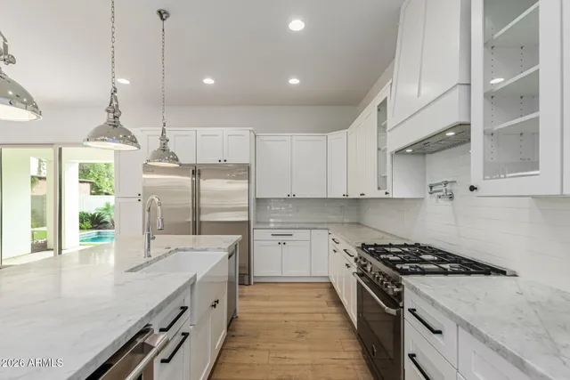 a kitchen with stainless steel appliances granite countertop cabinets a sink and a chandelier
