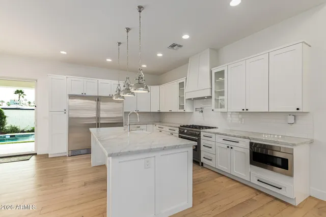 a kitchen with stainless steel appliances granite countertop a sink a refrigerator and a stove with wooden floors