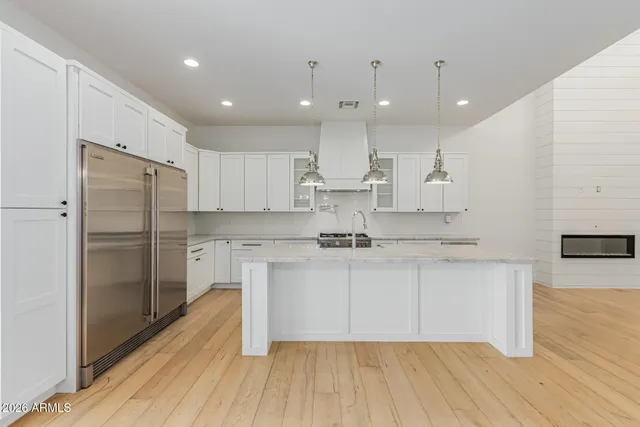 a view of empty room with wooden floor and kitchen
