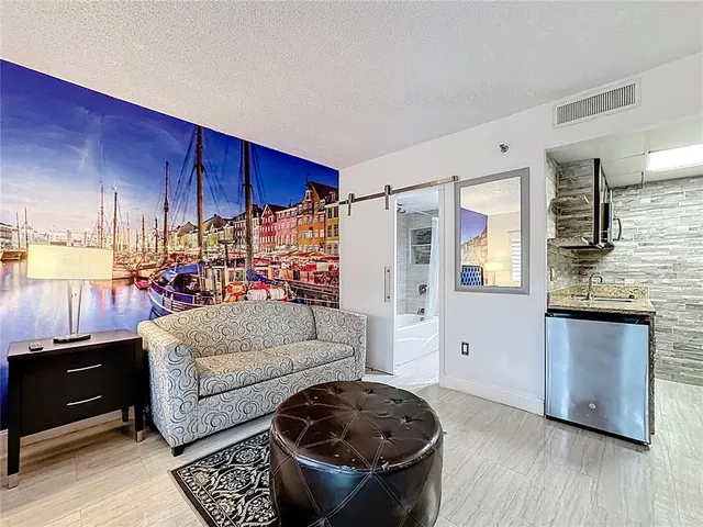 a living room with stainless steel appliances kitchen island granite countertop furniture and a wooden floor