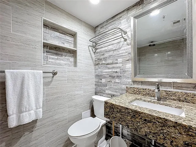 a bathroom with a granite countertop toilet a sink and a mirror