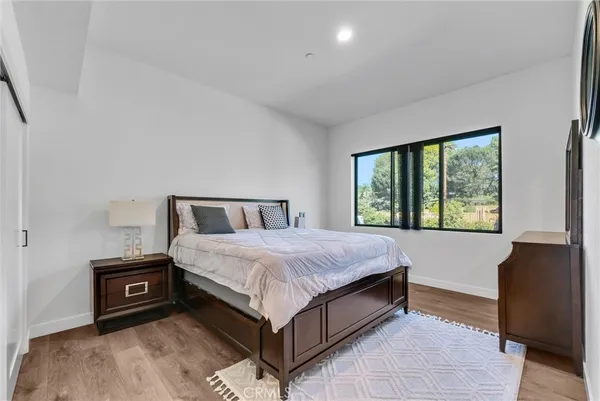 a bedroom with a bed a large window with table and chair