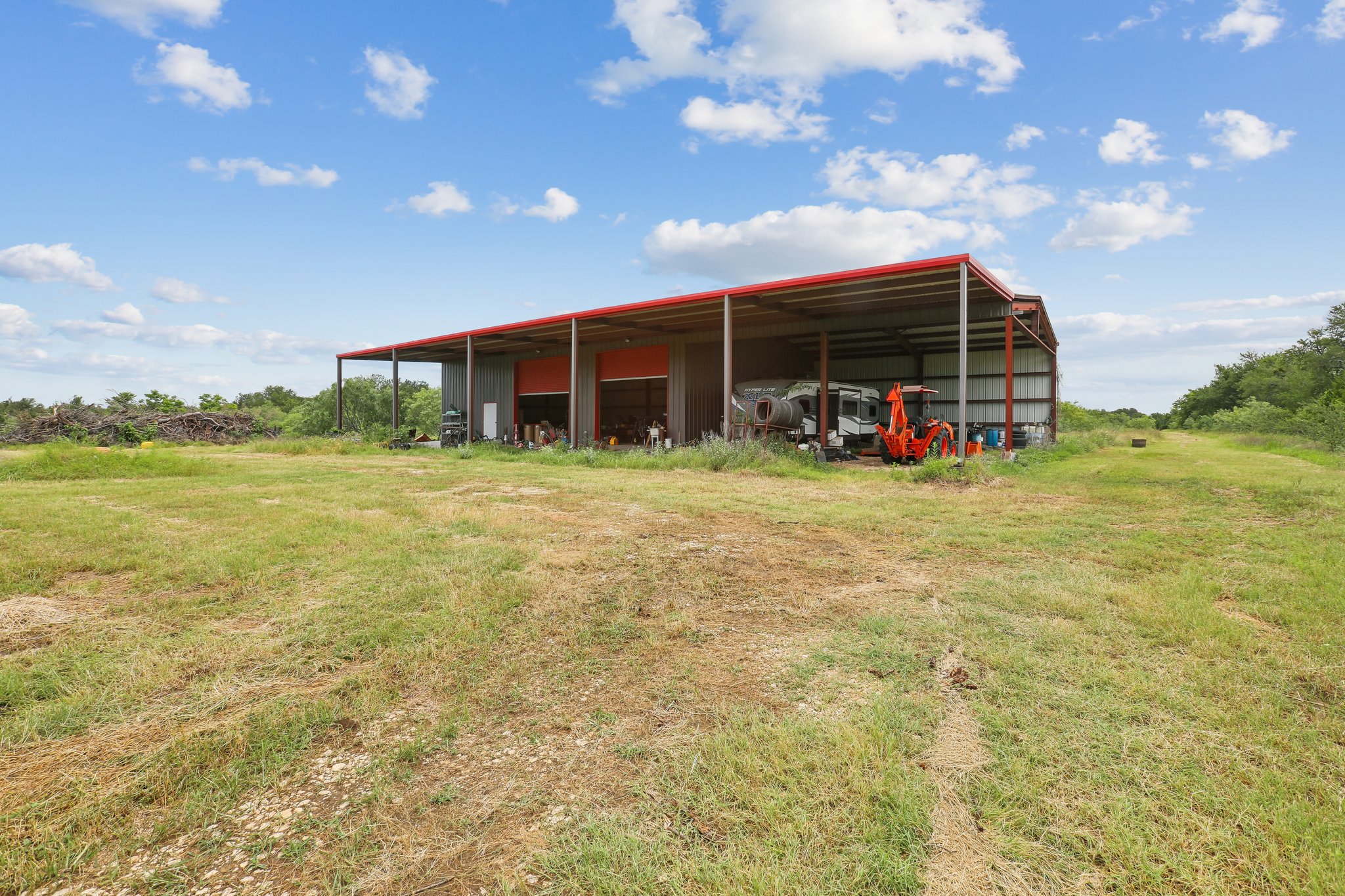 406 Monkey Road Elgin, TX 78621 - Photo 30 of 39 Spacious metal building featuring a red-trimmed roof and multiple bay openings