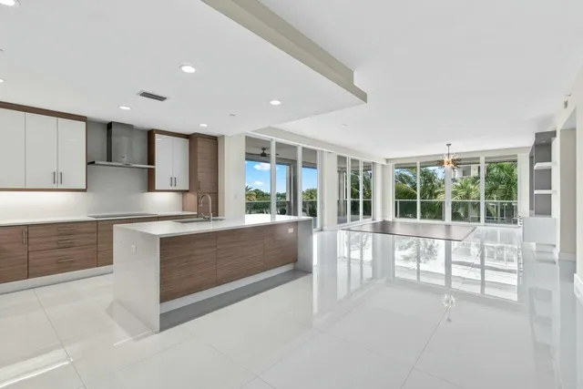 a large white kitchen with a sink and dishwasher a stove top oven with wooden floor