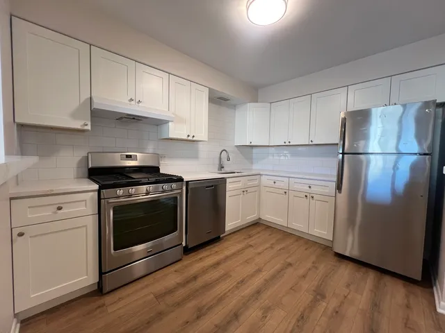 a white kitchen with sink a refrigerator and white cabinets