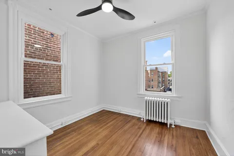 a view of empty room with wooden floor and fan
