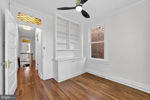 a view of an empty room with a window and wooden floor