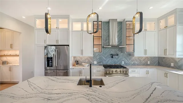 a kitchen with stainless steel appliances a sink a stove and white cabinets with wooden floor