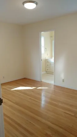 a view of empty room with wooden floor and window