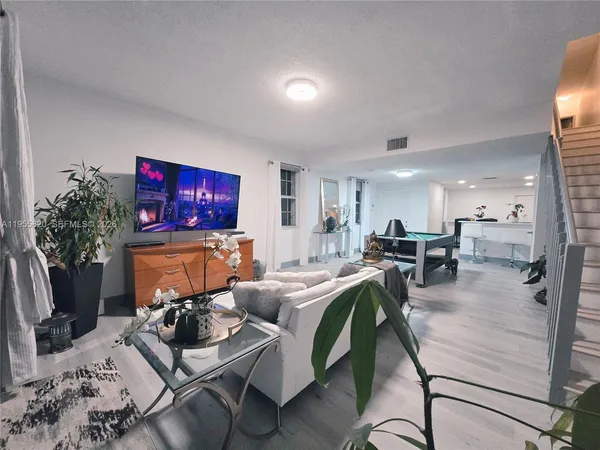 a living room with furniture a flat screen tv and kitchen area