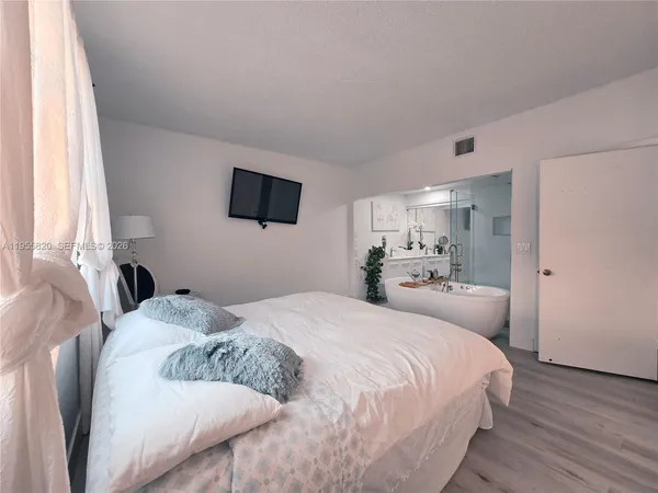 a bedroom with a bed and a flat tv screen on the dresser