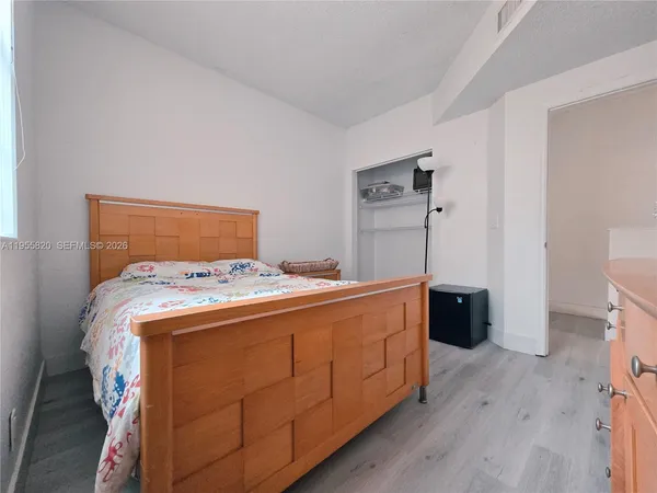 a bed sitting in a bedroom and dressers next to a window