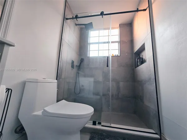 a bathroom with a shower a toilet and a window