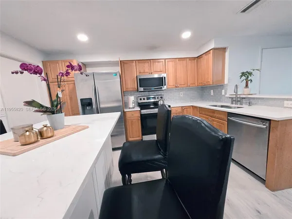 a kitchen with stainless steel appliances kitchen island granite countertop a sink dishwasher and cabinets with wooden floor