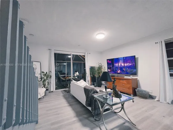a living room with furniture a floor to ceiling window and wooden floor