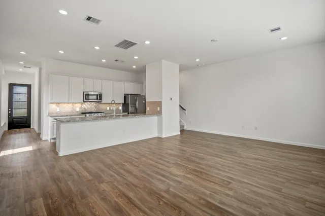 a view of kitchen with kitchen island a sink wooden floor and white stainless steel appliances
