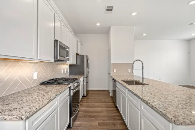 a kitchen with stainless steel appliances granite countertop a stove a sink and a refrigerator