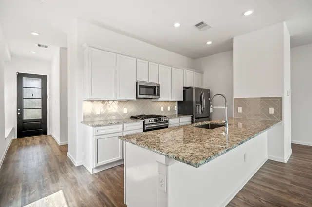 a kitchen with kitchen island granite countertop a stove sink and microwave