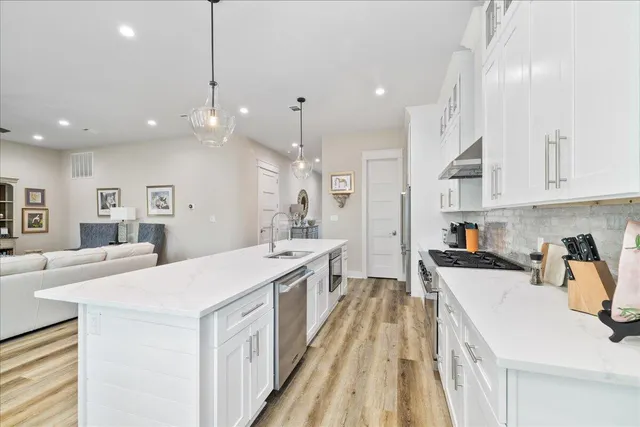 a large kitchen with kitchen island a stove a sink a refrigerator and a dining table with wooden floor