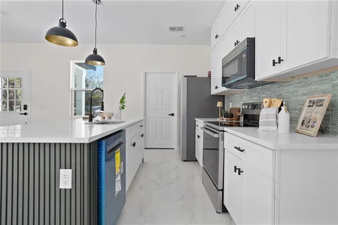 a kitchen with stainless steel appliances a sink a stove a refrigerator cabinets and a window