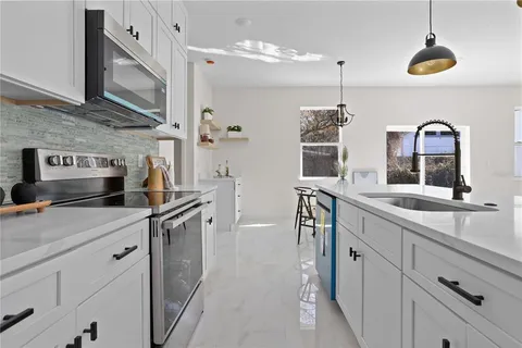 a kitchen with stainless steel appliances granite countertop a sink a stove and a wooden floors