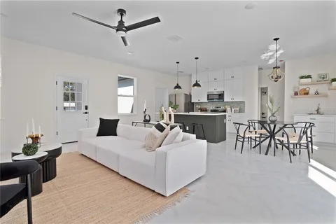 a living room with furniture kitchen view and a chandelier