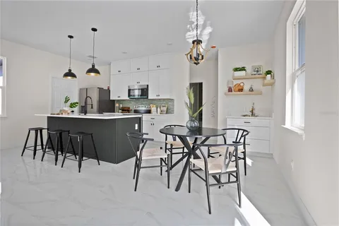 a dining room filled chandelier and kitchen view