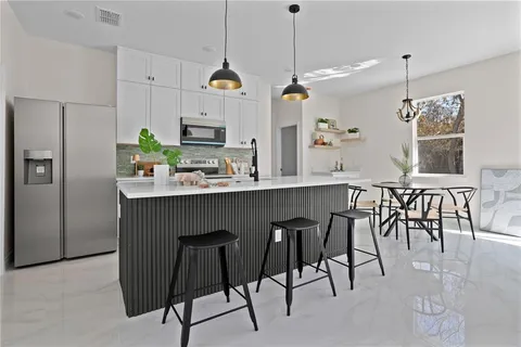 a kitchen with stainless steel appliances kitchen island granite countertop a table chairs sink and cabinets