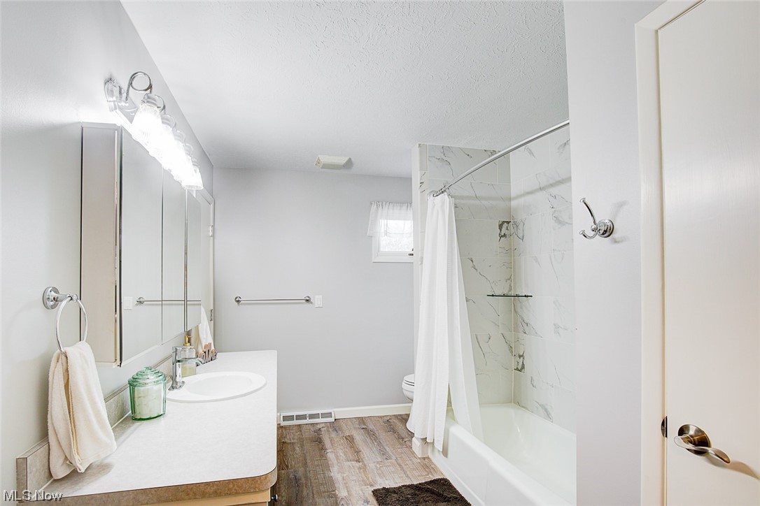 31950 Cannon Road Solon, OH 44139 - Photo 19 of 33 Full bathroom with large vanity, a textured ceiling, mirror, light hardwood flooring, and shower / bathtub combination with curtain
