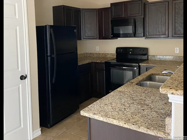 a kitchen with stainless steel appliances granite countertop a refrigerator and a stove top oven