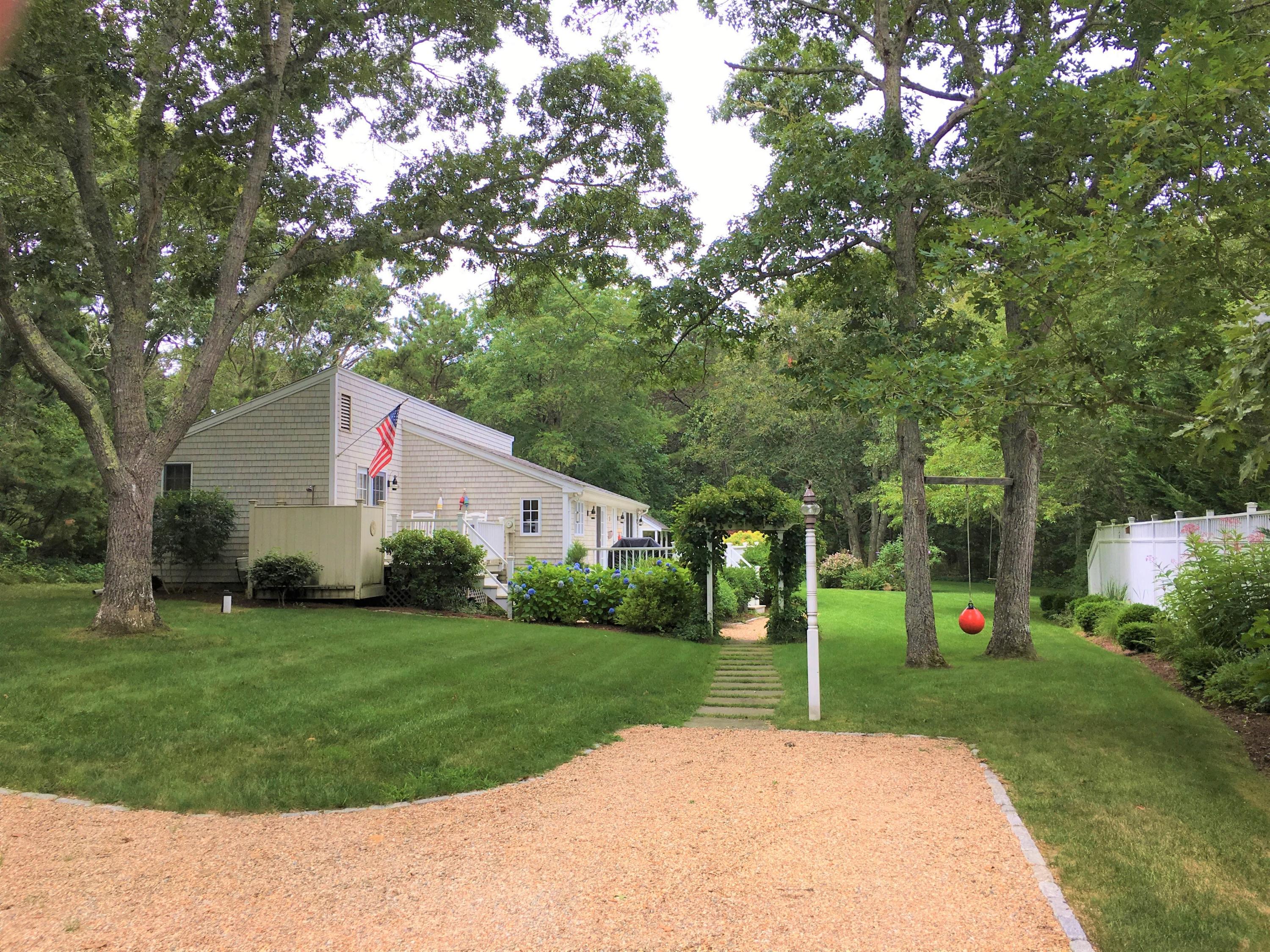 a backyard of a house with plants and large tree