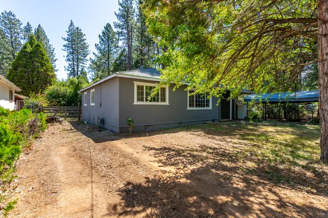 a backyard of a house with large trees and outdoor seating