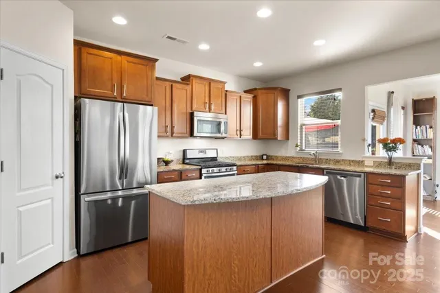 a kitchen with stainless steel appliances granite countertop a refrigerator a sink a stove a microwave and island