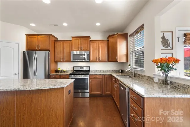 a kitchen with stainless steel appliances granite countertop a sink stove refrigerator and cabinets