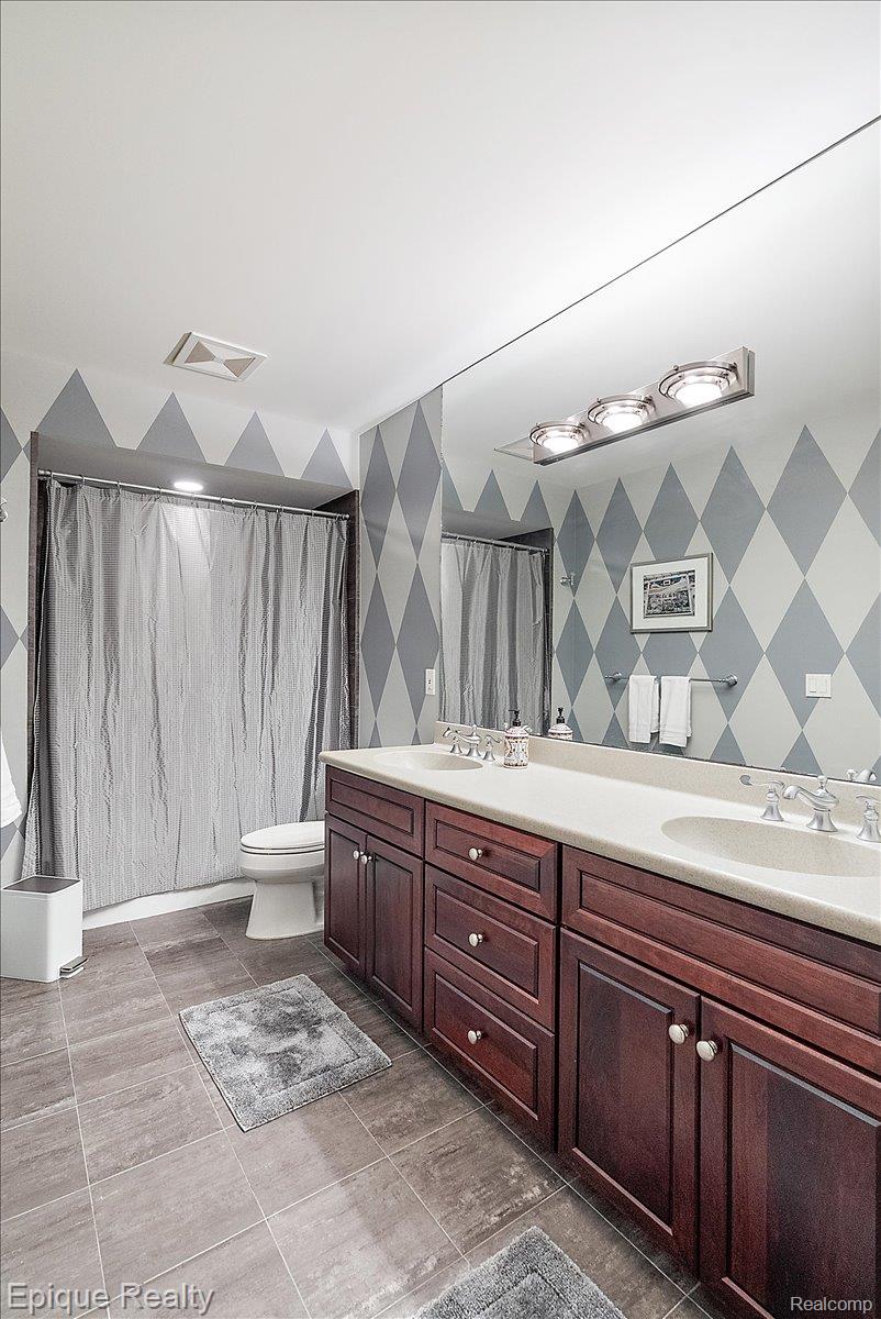 7662 Devins Ridge Clarkston, MI 48348 - Photo 81 of 81 Bathroom featuring a double vanity with dark wood cabinetry, white countertops, dual undermount sinks, and a full-width mirror