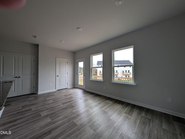 a view of an empty room with wooden floor and window