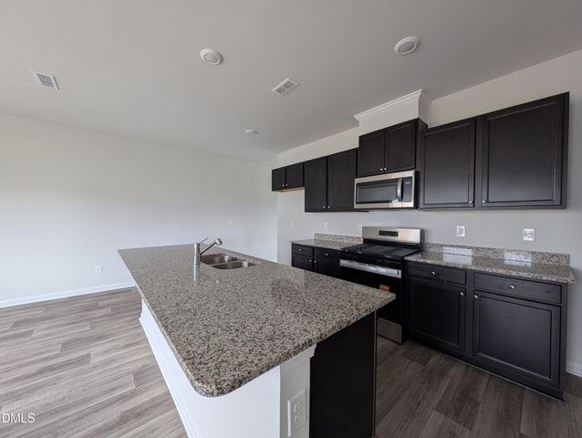 a kitchen with kitchen island granite countertop a sink dishwasher stove and oven with wooden floor