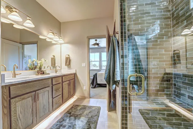 a spacious bathroom with a double vanity sink a mirror and next to a window