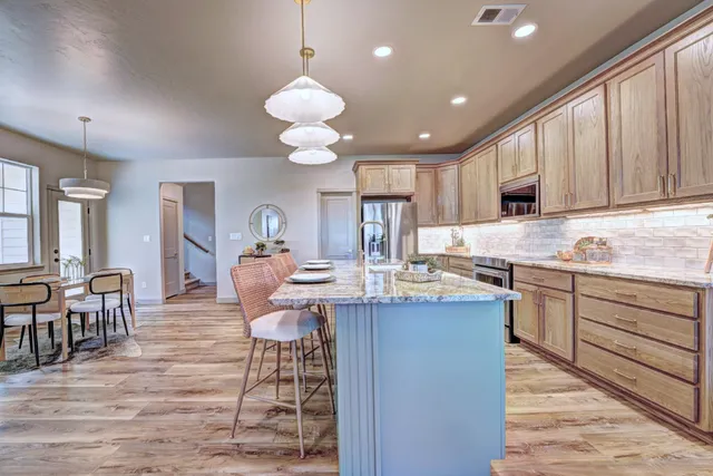 a kitchen with kitchen island granite countertop a sink cabinets and wooden floor
