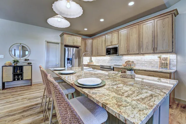 a kitchen with granite countertop kitchen island stainless steel appliances a sink stove and cabinets