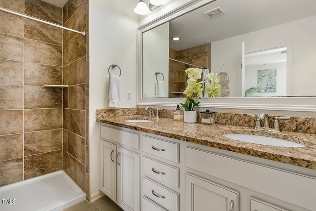 a bathroom with a granite countertop sink a mirror and a shower