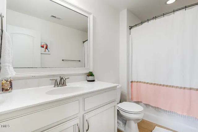 a bathroom with a sink a toilet a mirror and shower curtain