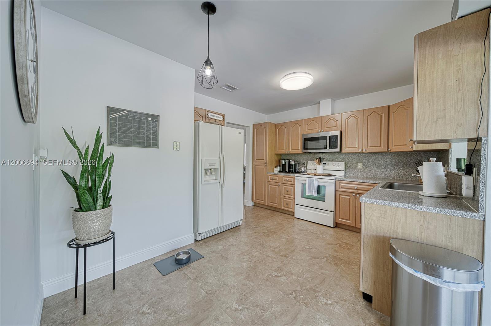 10600 Southwest 80th Court Miami, FL 33156 - Photo 10 of 51 a kitchen with stainless steel appliances granite countertop a refrigerator a stove a sink dishwasher and white cabinets with wooden floor