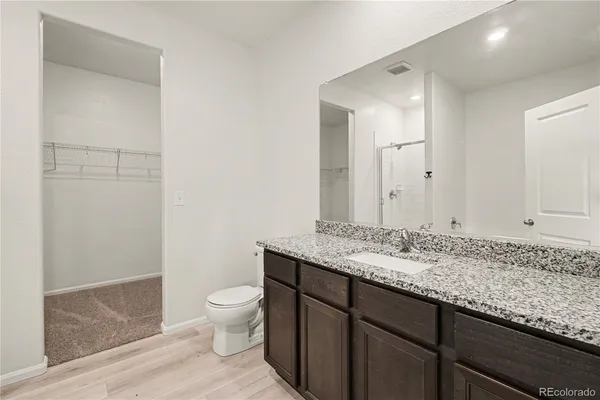 a bathroom with a granite countertop sink a toilet and a mirror