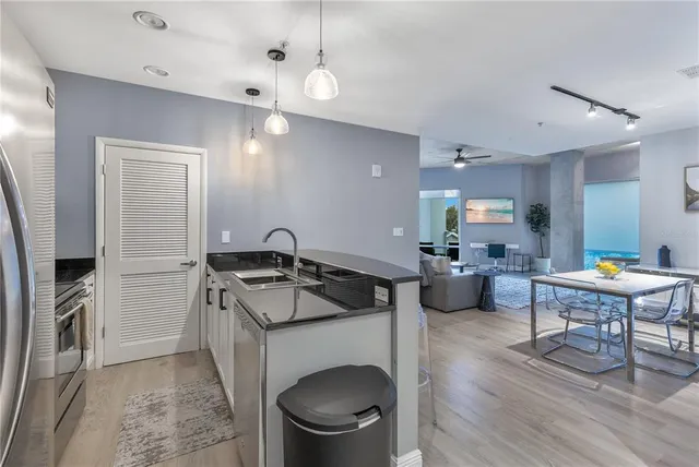 a kitchen with stainless steel appliances granite countertop a refrigerator a stove and a sink with wooden floor