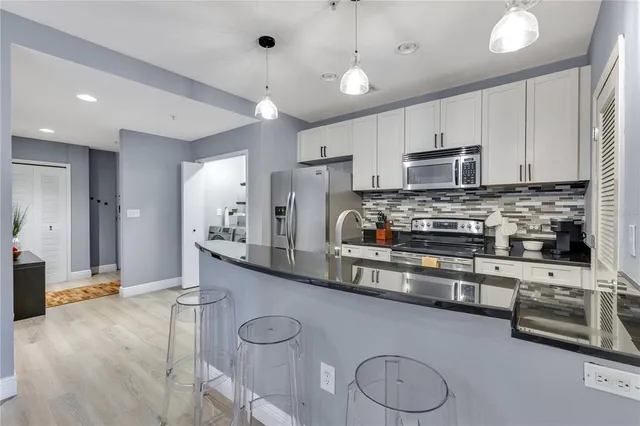 a kitchen with stainless steel appliances granite countertop a sink refrigerator and cabinets