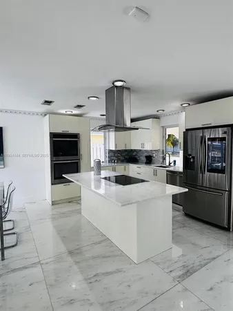 a large white kitchen with a stove a sink a microwave and dining table